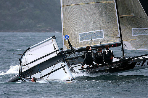 Western Australia&rsquo;s SLAM skippered by Grant Rollerson passes by a capsised Moth, during Race 12 of the Club Championship Race. Photo copyright Australian 18 Footers League.
